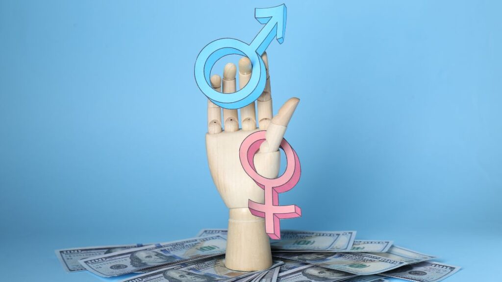 A mannequin hand holding up the male and female symbols with a pile of money strewn around