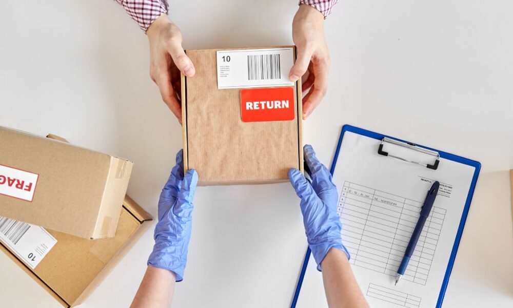 A pair of hands giving a return package to a gloved pair of hands to process