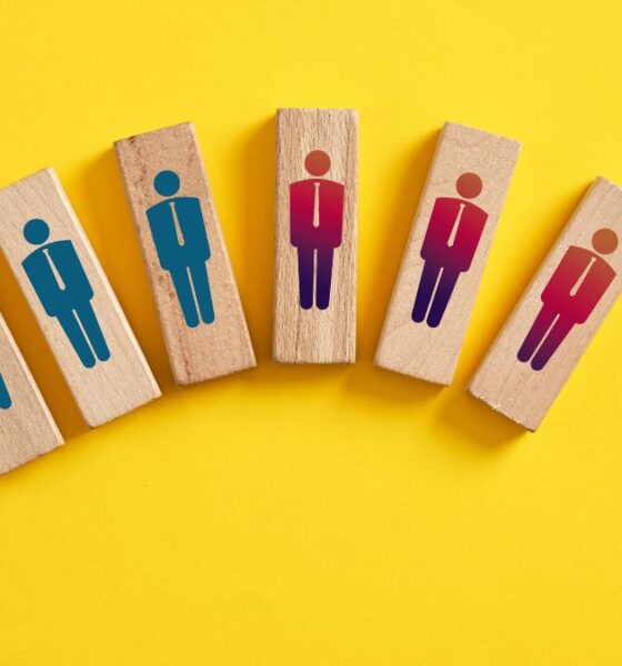 Wooden blocks that have worker graphics on them. Some are blue and and some are red to indicated laid off employees.