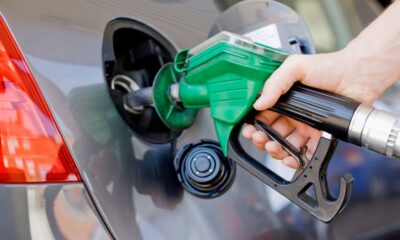 Closeup of hand holding a green gas pump filling up car