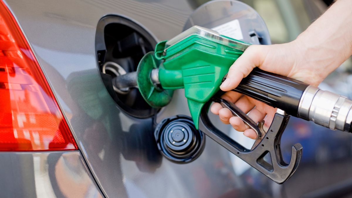 Closeup of hand holding a green gas pump filling up car